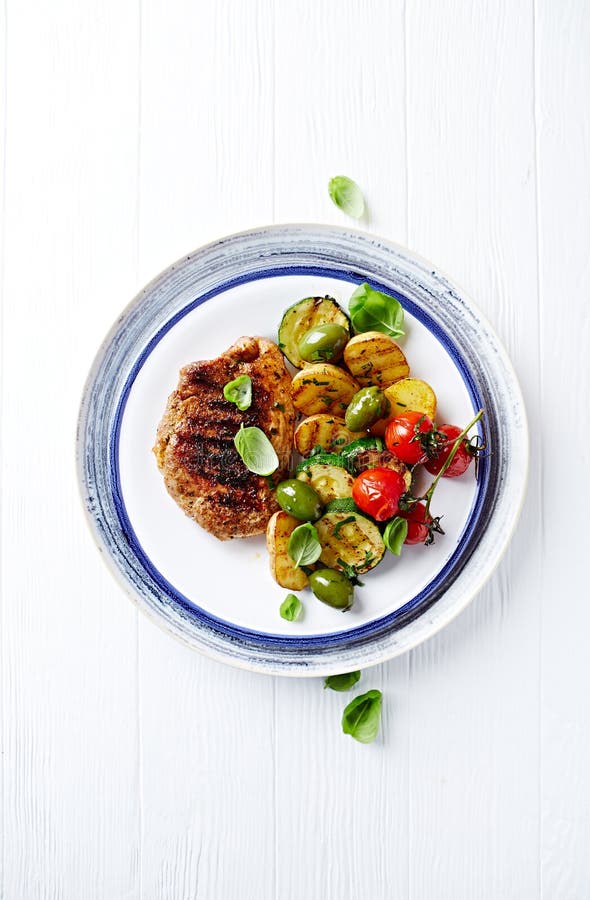 Gegrilltes Truthahnsteak mit Gemüse und frischem Basilikum verlässt auf einer Platte stockfotografie