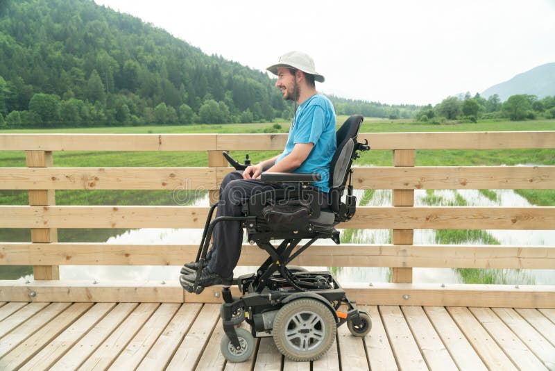 Gehandicapte jonge man in een elektrische rolstoel op een wandeling die zijn vrijheid geniet en de natuur observeert royalty-vrije stock afbeeldingen Gehandicapte jonge man in een elektrische rolstoel op een wandeling die zijn vrijheid geniet en de natuur observeert royalty-vrije stock afbeeldingen