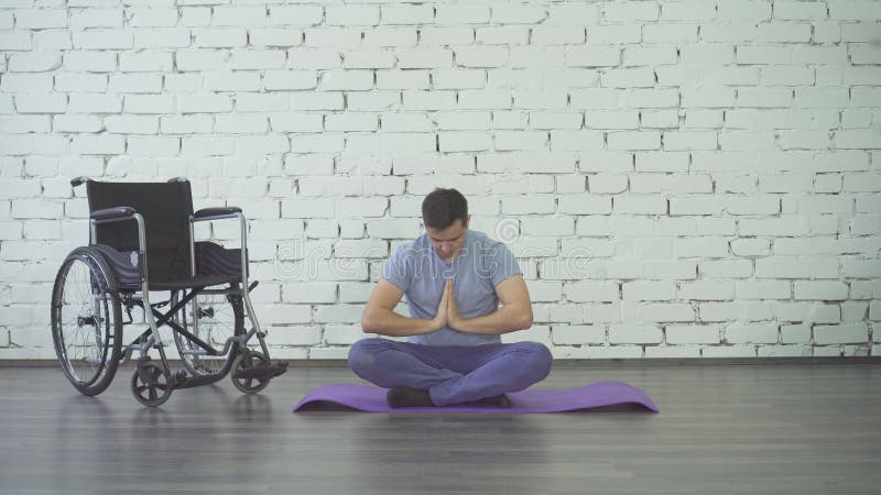 Gehandicapte mens die yoga, rolstoel en oefeningsmat doen stock foto Gehandicapte mens die yoga, rolstoel en oefeningsmat doen stock foto