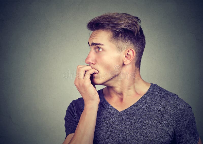 Geheel in beslag genomen bezorgde jonge mens die zijn vingernagels bijten die aan de kant kijken stock foto's Geheel in beslag genomen bezorgde jonge mens die zijn vingernagels bijten die aan de kant kijken stock foto's