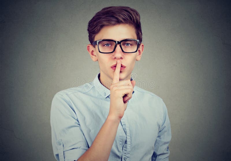 Secret guy. Man saying hush be quiet with finger on lips gesture looking at camera isolated on gray wall background. Secret guy. Man saying hush be quiet with finger on lips gesture looking at camera isolated on gray wall background.