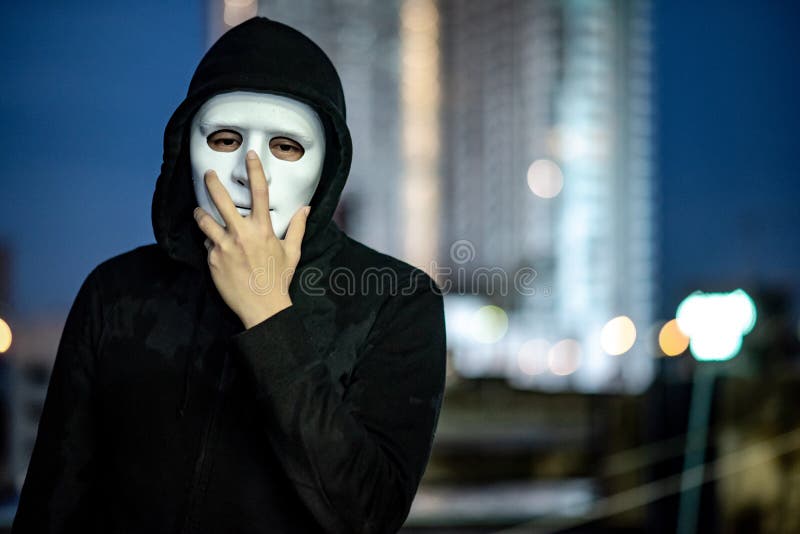 Geheimzinnigheid mens in wit masker die zich op dak bevinden royalty-vrije stock fotografie Geheimzinnigheid mens in wit masker die zich op dak bevinden royalty-vrije stock fotografie