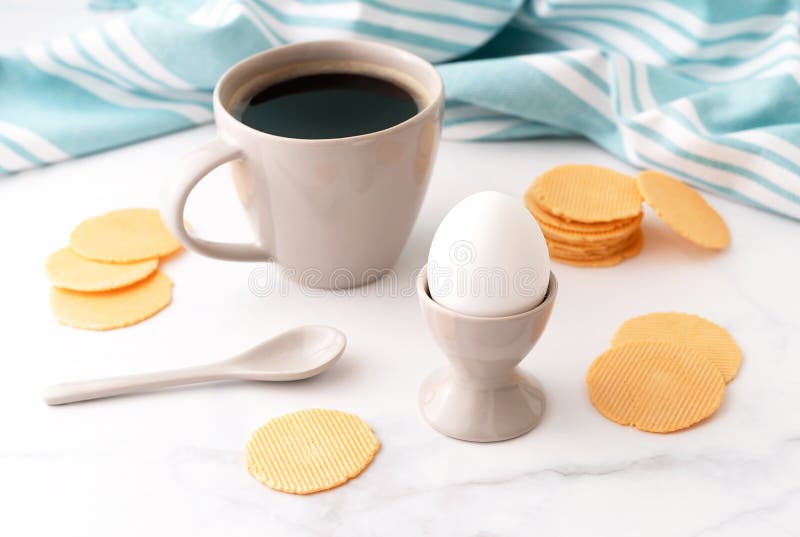 Gekochtes Ei im keramischen Eierbecher, im Tasse Kaffee und in den dünnen knusperigen Corn chipen auf Hintergrund des Türkisgesch stockbild Gekochtes Ei im keramischen Eierbecher, im Tasse Kaffee und in den dünnen knusperigen Corn chipen auf Hintergrund des Türkisgesch stockbild