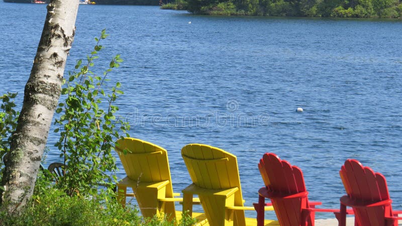 Gekommen entspannen Sie sich auf den Muskoka-Stühlen, die den See gegenüberstellen lizenzfreies stockfoto Gekommen entspannen Sie sich auf den Muskoka-Stühlen, die den See gegenüberstellen lizenzfreies stockfoto