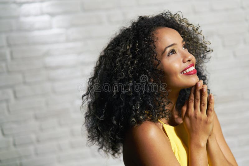 Portrait of happy latina woman smiling and saying prayer. Black girl looking up while praying. Portrait of happy latina woman smiling and saying prayer. Black girl looking up while praying.