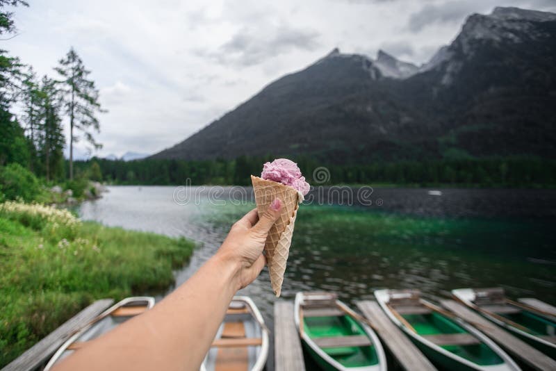 Gelado fêmea da posse da mão no lado do lago na montanha fotografia de stock Gelado fêmea da posse da mão no lado do lago na montanha fotografia de stock