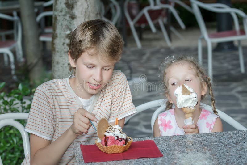 Gelato italien de consommation de garçon et de fille dans la barre de crème glacée de rue images libres de droits