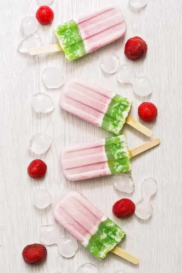 Gelato verde rosa su un bastone su un fondo di legno bianco Gelato del kiwi e della fragola fotografia stock libera da diritti Gelato verde rosa su un bastone su un fondo di legno bianco Gelato del kiwi e della fragola fotografia stock libera da diritti