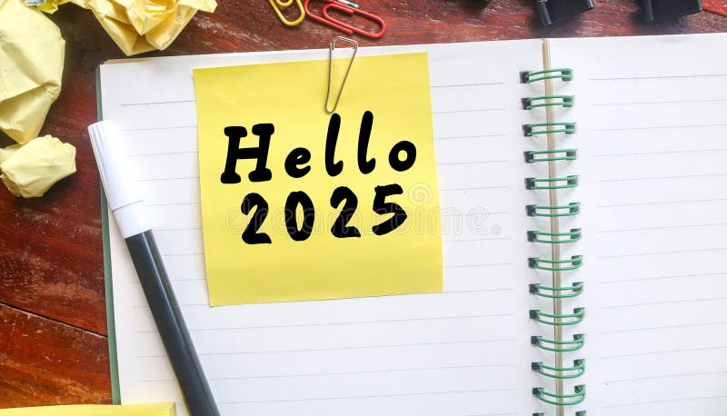 Gelbe klebrige Note mit hello 2025 auf einem Notebook mit Schreibwaren. lizenzfreie stockfotografie