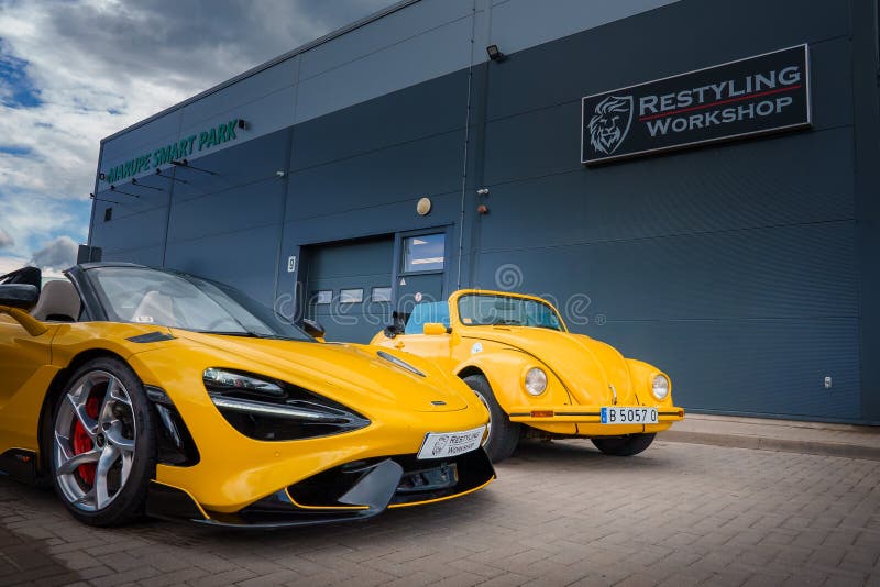 A vivid yellow McLaren 765LT, doors ajar, is parked next to an old VW Beetle at a Restyling Workshop, displaying a mix of modern and classic auto designs under a semicloudy sky. A vivid yellow McLaren 765LT, doors ajar, is parked next to an old VW Beetle at a Restyling Workshop, displaying a mix of modern and classic auto designs under a semicloudy sky.