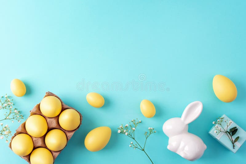 Gelbe Ostereier weiße, sonnige Geschenkbox und Blumen auf blauem Hintergrund. Top-Ansicht-Bildkopplerraum lizenzfreies stockbild