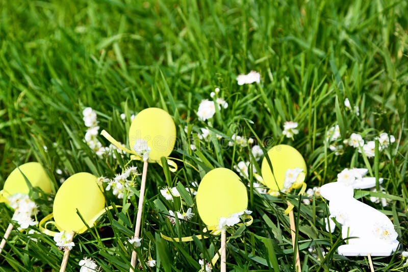 Gelbe Ostereier, weißes Kaninchen und Blumen sind auf frischem Frühlingsgras im Garten stockbilder