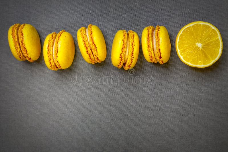 Gelbe Zitrusmakronen und eine Scheibe einer frisch geschnittenen Zitrone auf grauem Hintergrund