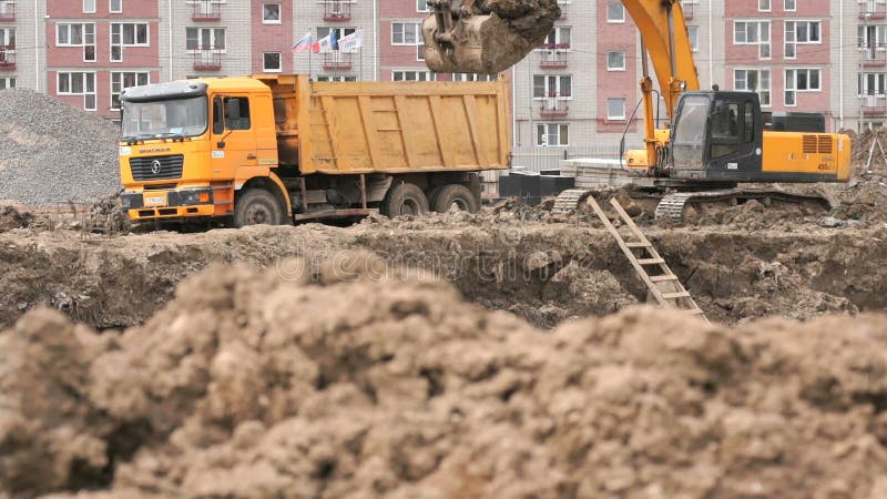 Gelber Bagger lädt Lehm unter Verwendung seines großen Eimers