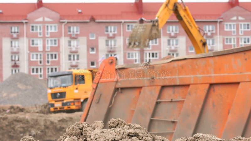 Gelber Bagger lädt Lehm unter Verwendung seines großen Eimers