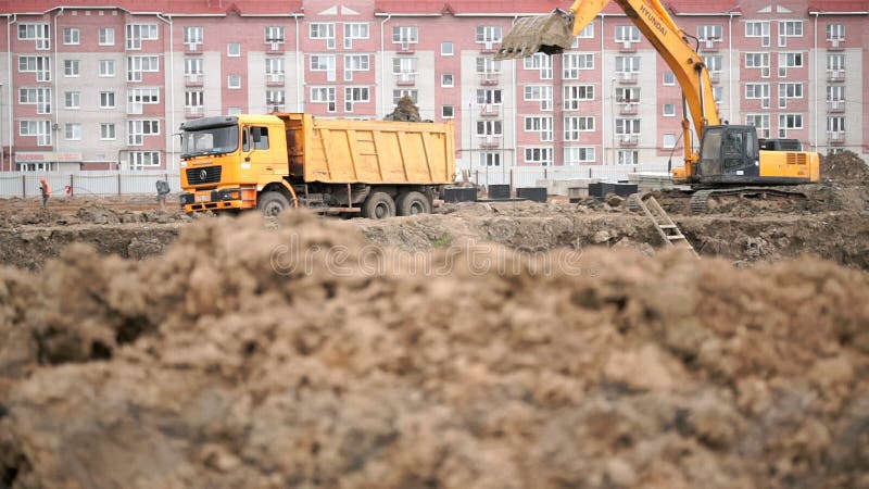 Gelber Bagger lädt Lehm unter Verwendung seines großen Eimers