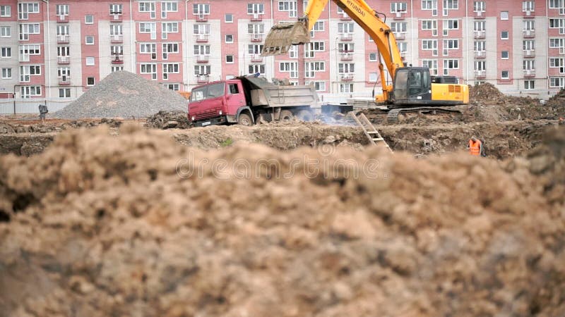 Gelber Bagger lädt Lehm unter Verwendung seines großen Eimers