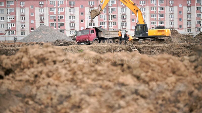 Gelber Bagger lädt Lehm unter Verwendung seines großen Eimers