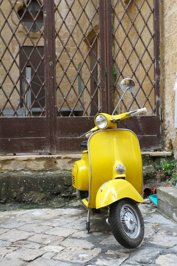 Gelber Weinleseroller geparkt vor einem tipical Haus in einem Dorf von Salento, Italien Ein des populärsten Transportes herein stockbild Gelber Weinleseroller geparkt vor einem tipical Haus in einem Dorf von Salento, Italien Ein des populärsten Transportes herein stockbild