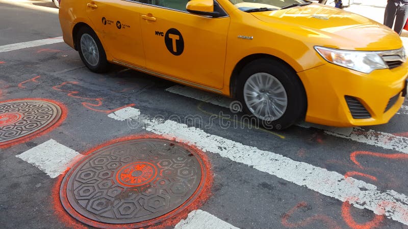 Gelbes NYC-Taxi, das auf die Straße mit manhaole Abdeckungen fährt