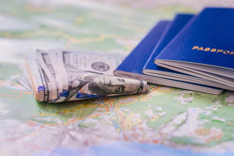 Geldbundels en internationale paspoorten staan bovenaan de toeristische kaart Het geld en de documenten staan op de wereldkaart S