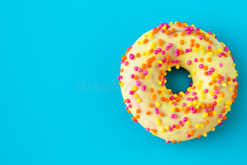 Gele donut op een blauwe achtergrond met kopieerruimte Multicolortopping op gele beglazing Ongezond, calorierijk voedsel