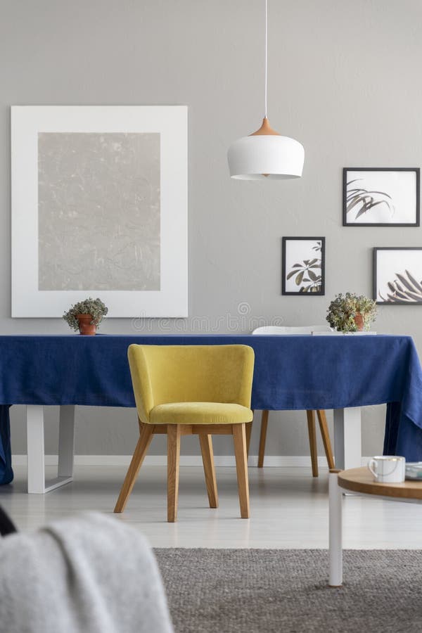 Gele houten stoel bij lijst met blauwe doek in modern eetkamerbinnenland met model royalty-vrije stock afbeeldingen Gele houten stoel bij lijst met blauwe doek in modern eetkamerbinnenland met model royalty-vrije stock afbeeldingen