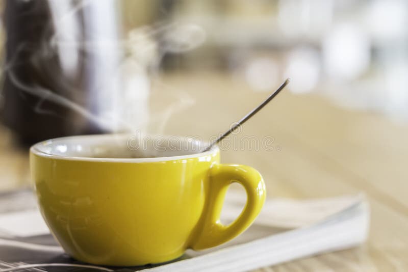 Gele mok op tijdschrift in koffie stock fotografie