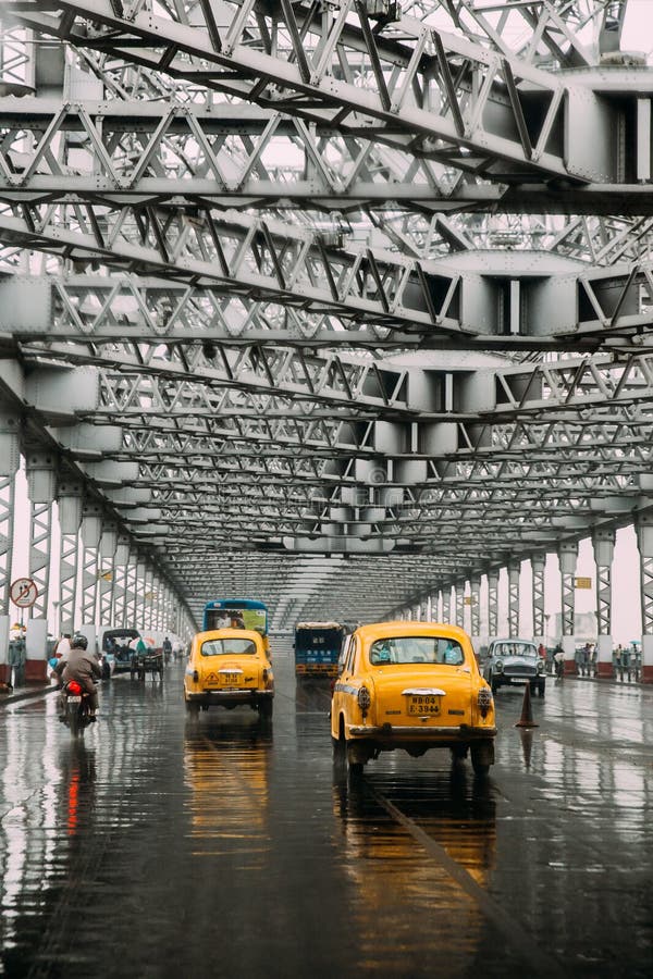 Gele taxis die op de weg binnen de Brug van Howrah in de middag met regen in Kolkata, India lopen