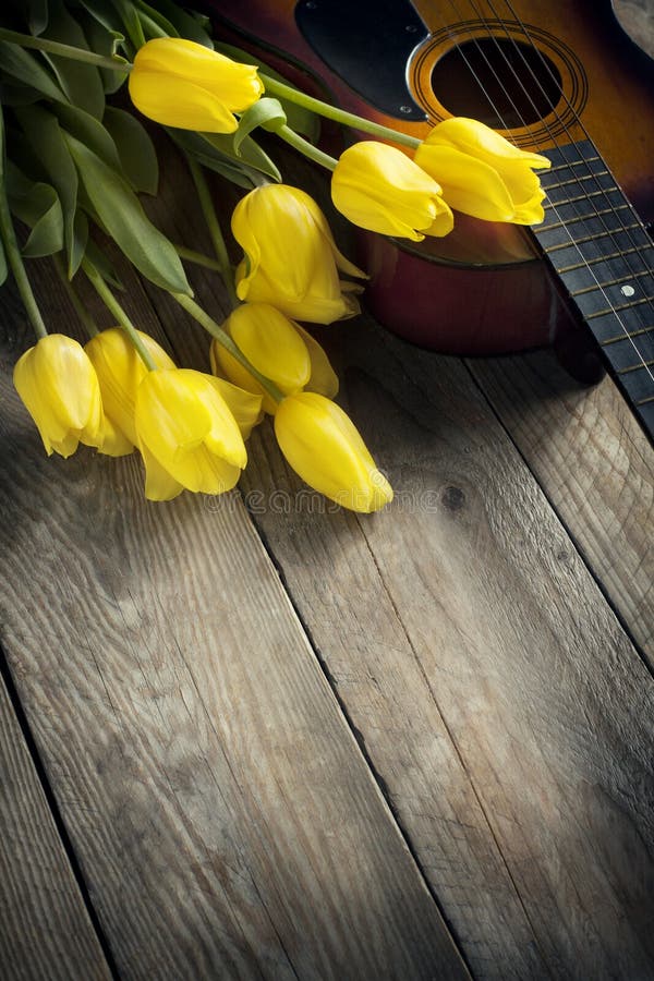 Gele tulpen en gitaar op oude houten oppervlakte stock afbeeldingen Gele tulpen en gitaar op oude houten oppervlakte stock afbeeldingen