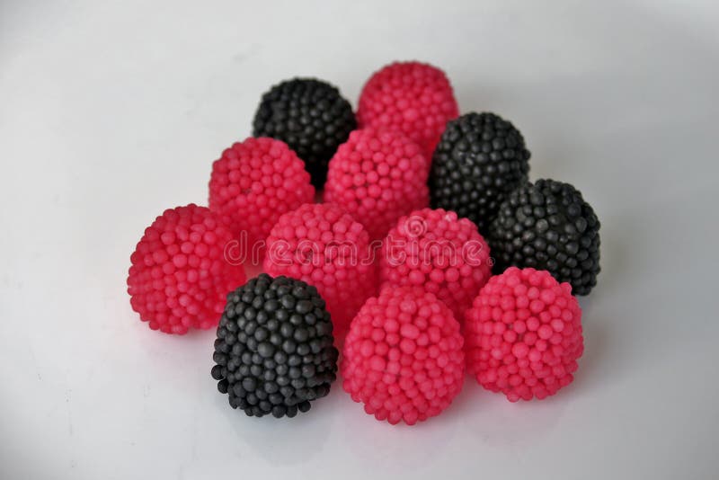 Gelees??igkeiten in Form von Himbeeren, rot und schwarz auf einem wei?en Hintergrund lizenzfreies stockbild Gelees??igkeiten in Form von Himbeeren, rot und schwarz auf einem wei?en Hintergrund lizenzfreies stockbild