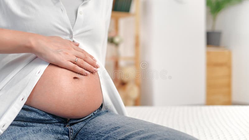 Gelegentlich zukünftige Mutter schwanger Frau berühren Tummy warten Baby Geburt mit Liebe Weiße Zimmer Nähe