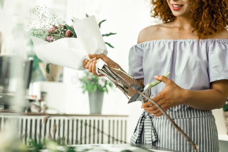Gelockter rothaariger Florist mit den hellen Lippen, die schönen netten Blumenstrauß beenden lizenzfreie stockfotografie Gelockter rothaariger Florist mit den hellen Lippen, die schönen netten Blumenstrauß beenden lizenzfreie stockfotografie