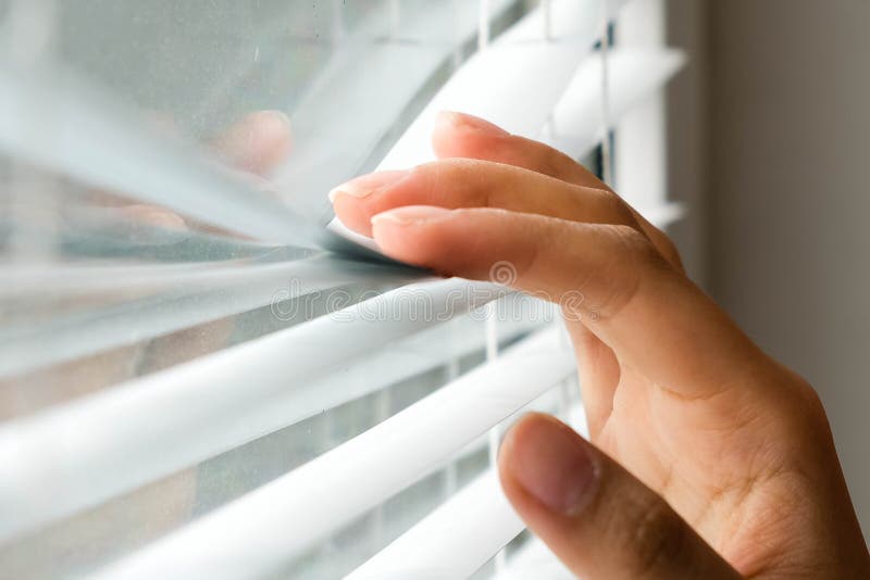 Gelosia di Windows donna che dà una occhiata attraverso i ciechi di finestra Mano maschio che separa le stecche delle veneziane c fotografia stock libera da diritti Gelosia di Windows donna che dà una occhiata attraverso i ciechi di finestra Mano maschio che separa le stecche delle veneziane c fotografia stock libera da diritti