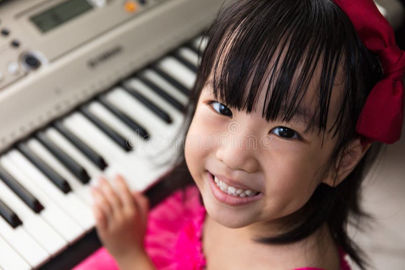 Gelukkig Aziatisch Chinees meisje dat elektrisch pianotoetsenbord speelt stock fotografie Gelukkig Aziatisch Chinees meisje dat elektrisch pianotoetsenbord speelt stock fotografie