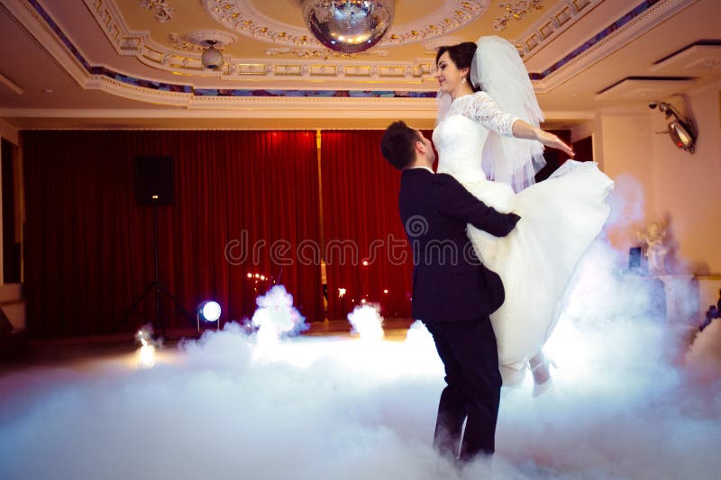 Gelukkig elegant schitterend echtpaar die eerste dans met zwaar rook en vuurwerk in een modieus restaurant uitvoeren stock fotografie Gelukkig elegant schitterend echtpaar die eerste dans met zwaar rook en vuurwerk in een modieus restaurant uitvoeren stock fotografie