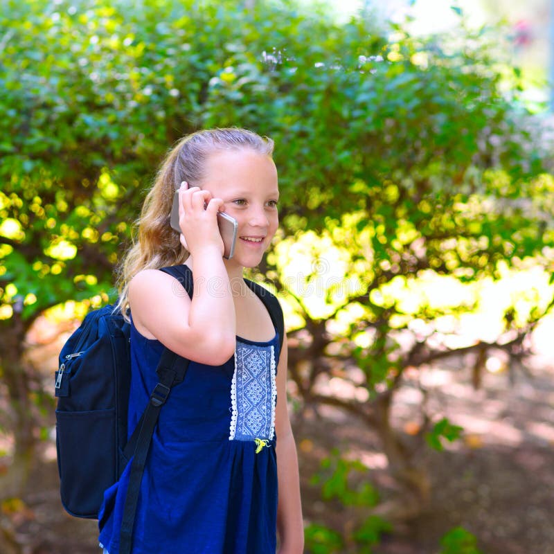 Gelukkig gaat weinig kindmeisje naar school en het spreken op mobiele telefoon bij stadspark royalty-vrije stock foto Gelukkig gaat weinig kindmeisje naar school en het spreken op mobiele telefoon bij stadspark royalty-vrije stock foto