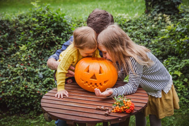 Gelukkig Halloween De vader en twee dochters kijken buiten binnen de gesneden pompoen voor Halloween stock foto's Gelukkig Halloween De vader en twee dochters kijken buiten binnen de gesneden pompoen voor Halloween stock foto's