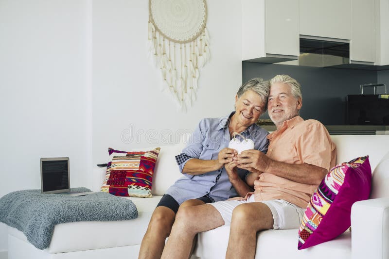 Gelukkig hoger volwassen paar van cacuasian mensen in liefdezitting thuis op de bank en het nemen van een houten hand - gemaakte royalty-vrije stock foto Gelukkig hoger volwassen paar van cacuasian mensen in liefdezitting thuis op de bank en het nemen van een houten hand - gemaakte royalty-vrije stock foto