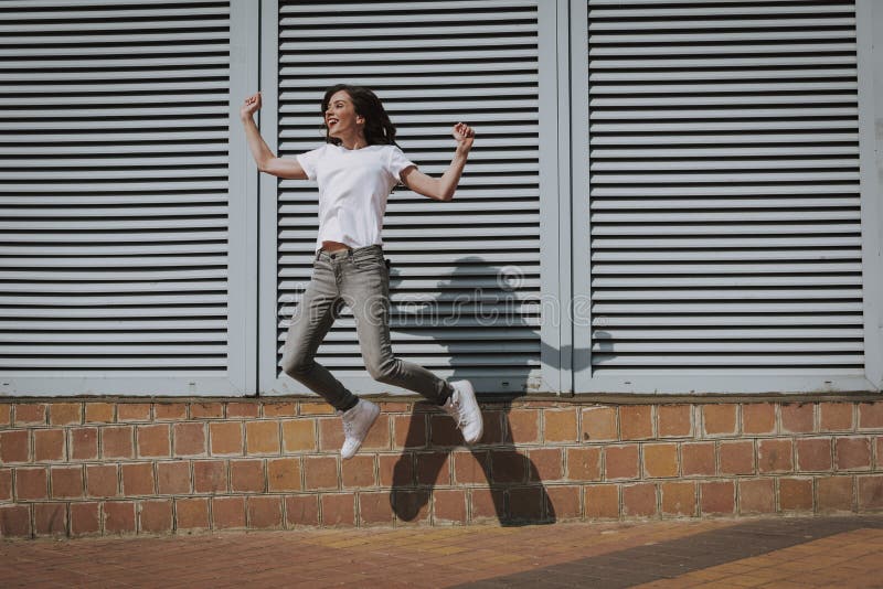 Gelukkig jong donkerbruin hipstermeisje die omhoog springen stock fotografie Gelukkig jong donkerbruin hipstermeisje die omhoog springen stock fotografie