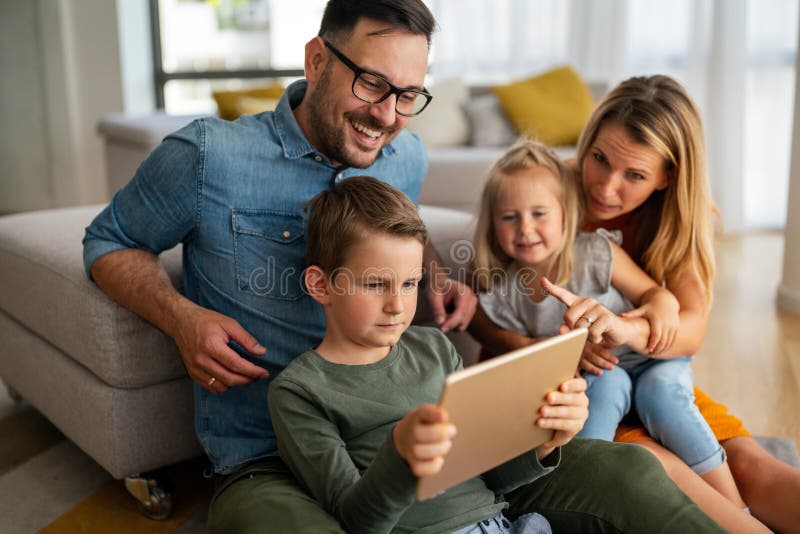 Gelukkig jong gezin met plezier thuis. ouders met kinderen die digitale apparatuur gebruiken.