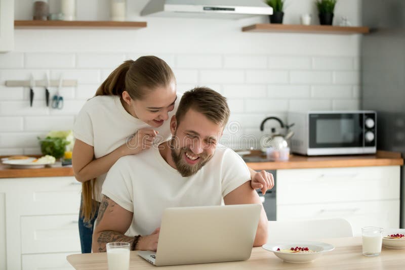 Gelukkig jong paar die laptop samen in de keuken met behulp van royalty-vrije stock afbeeldingen Gelukkig jong paar die laptop samen in de keuken met behulp van royalty-vrije stock afbeeldingen