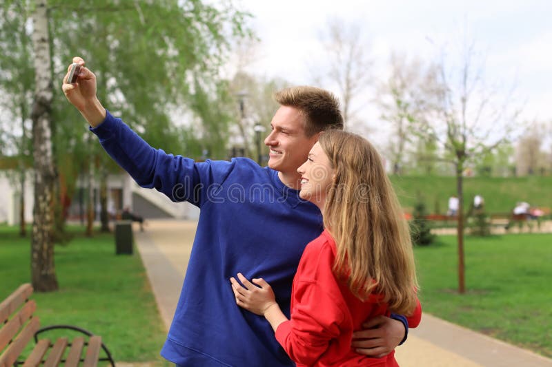 Gelukkig jong paar die selfie in park op de lentedag nemen royalty-vrije stock foto's Gelukkig jong paar die selfie in park op de lentedag nemen royalty-vrije stock foto's