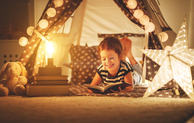 Gelukkig kindmeisje die en boek in dark in tent lezen bij ho lachen royalty-vrije stock foto's Gelukkig kindmeisje die en boek in dark in tent lezen bij ho lachen royalty-vrije stock foto's