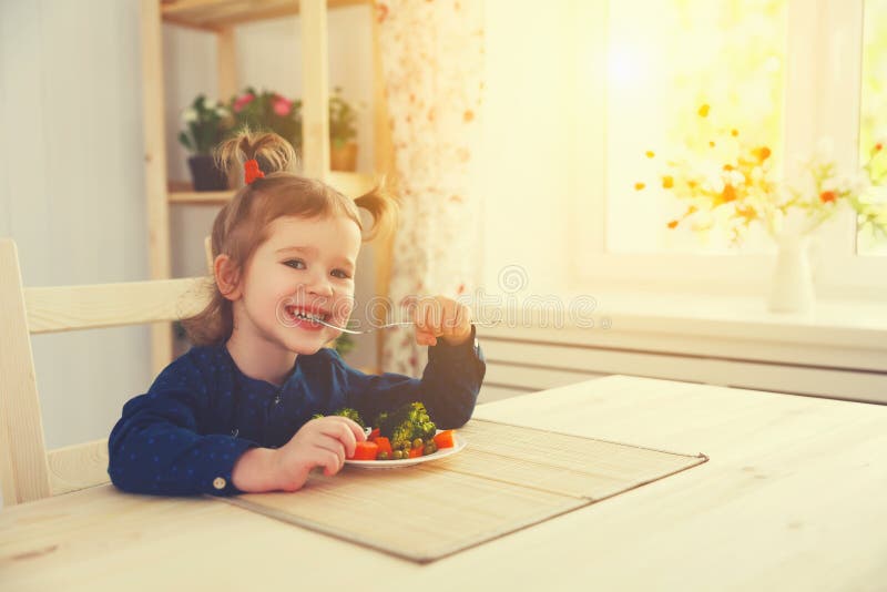 Gelukkig kindmeisje die groenten en lach eten stock fotografie Gelukkig kindmeisje die groenten en lach eten stock fotografie