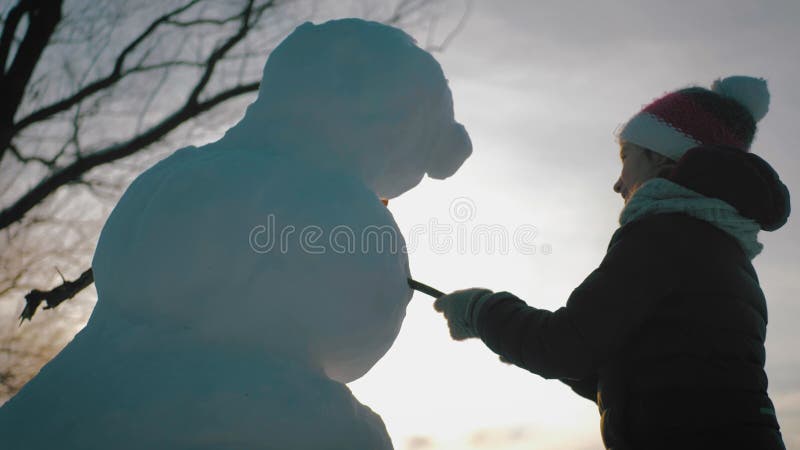 Gelukkig meisje bouwt een sneeuwpop in het winterpark. begrip wintervakantie en kerstmis.