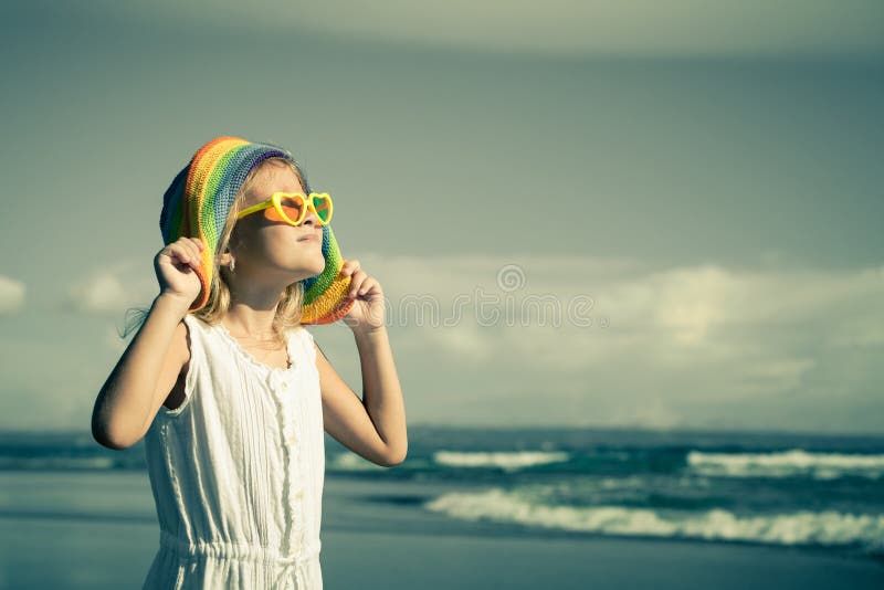 Gelukkig meisje in de hoed die zich op het strand bij de dag t bevinden royalty-vrije stock foto Gelukkig meisje in de hoed die zich op het strand bij de dag t bevinden royalty-vrije stock foto