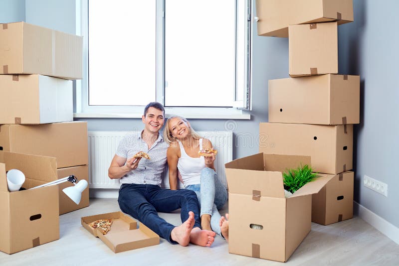 Gelukkig paar met pizza in een nieuwe flat voor een inwijdingsfeest stock afbeelding Gelukkig paar met pizza in een nieuwe flat voor een inwijdingsfeest stock afbeelding