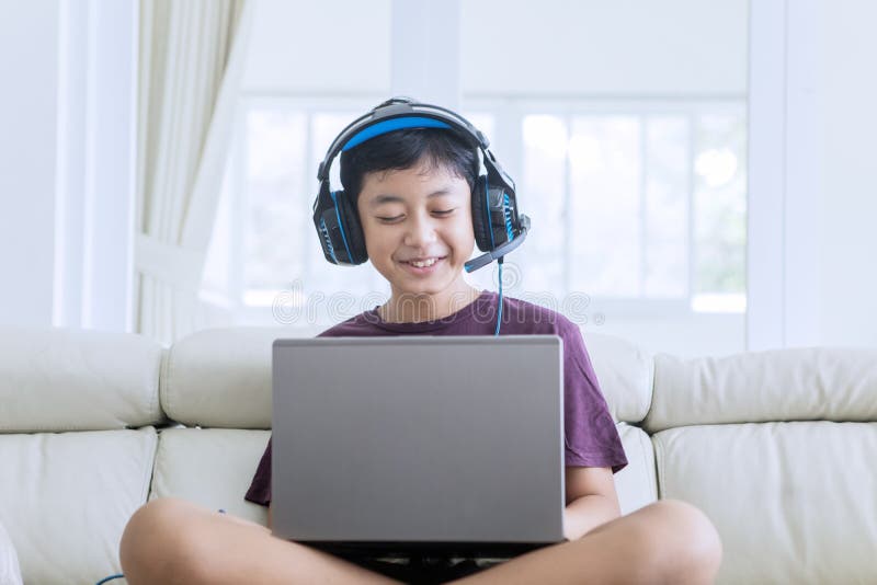Gelukkig preteen jongen gebruikend laptop en hoofdtelefoons royalty-vrije stock afbeeldingen Gelukkig preteen jongen gebruikend laptop en hoofdtelefoons royalty-vrije stock afbeeldingen