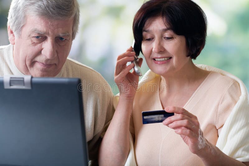 Happy elderly couple on laptop, shopping in internet shop or making card verification. Happy elderly couple on laptop, shopping in internet shop or making card verification